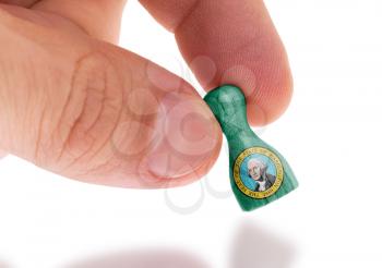 Hand holding wooden pawn with a flag painting, selective focus, Washington