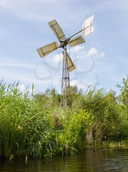 Small and rusted old metal windmill at the waterside, Netherlands