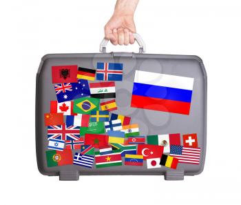Used plastic suitcase with lots of small stickers, large sticker of Russia