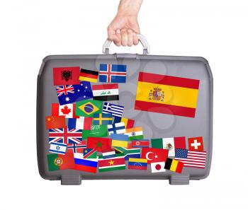 Used plastic suitcase with lots of small stickers, large sticker of Spain