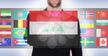 Hand pushing on a touch screen interface, choosing language or country, Iraq