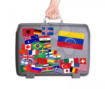 Used plastic suitcase with lots of small stickers, large sticker of Venezuela