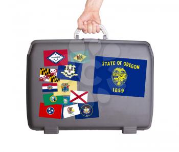 Used plastic suitcase with stains and scratches, stickers of US States, Oregon