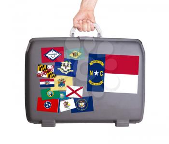 Used plastic suitcase with stains and scratches, stickers of US States, North Carolina