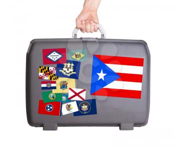 Used plastic suitcase with stains and scratches, stickers of US States, Puerto Rico