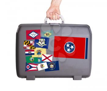 Used plastic suitcase with stains and scratches, stickers of US States, Tennessee
