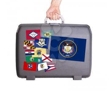 Used plastic suitcase with stains and scratches, stickers of US States, Utah