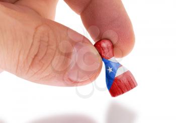 Hand holding wooden pawn with a flag painting, selective focus, Puerto Rico