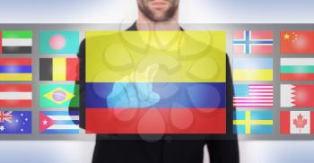Hand pushing on a touch screen interface, choosing language or country, Colombia