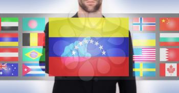 Hand pushing on a touch screen interface, choosing language or country, Venezuela
