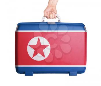 Used plastic suitcase with stains and scratches, printed with flag, North Korea