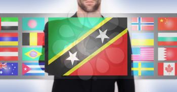 Hand pushing on a touch screen interface, choosing language or country, Saint Kitts and Nevis
