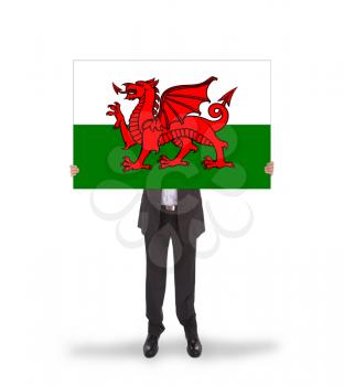 Businessman holding a big card, flag of Wales, isolated on white