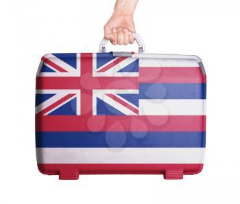 Used plastic suitcase with stains and scratches, printed with flag, Hawaii