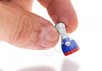 Hand holding wooden pawn with a flag painting, selective focus, Slovenia