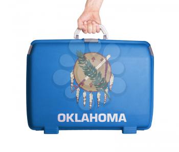 Used plastic suitcase with stains and scratches, printed with flag, Oklahoma