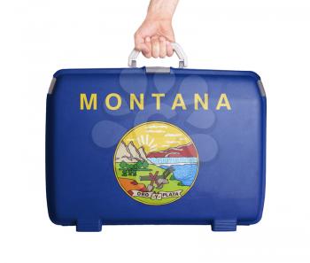 Used plastic suitcase with stains and scratches, printed with flag, Montana