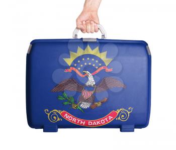Used plastic suitcase with stains and scratches, printed with flag, North Dakota
