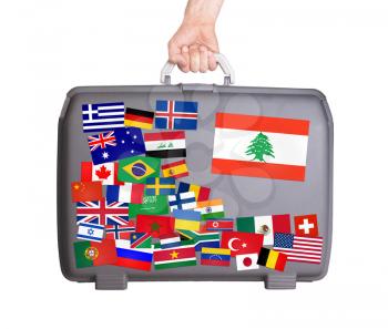 Used plastic suitcase with lots of small stickers, large sticker of Lebanon