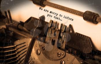 Close-up of an old typewriter with paper, selective focus, we are sorry to inform you that