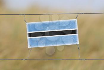Border fence - Old plastic sign with a flag - Botswana