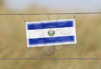 Border fence - Old plastic sign with a flag - El Salvador