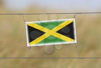 Border fence - Old plastic sign with a flag - Jamaica
