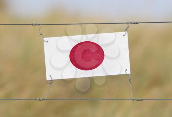 Border fence - Old plastic sign with a flag - Japan