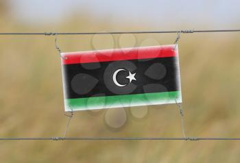Border fence - Old plastic sign with a flag - Libya