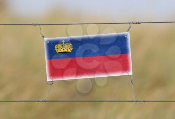 Border fence - Old plastic sign with a flag - Liechtenstein