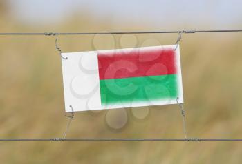 Border fence - Old plastic sign with a flag - Madagascar