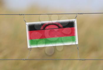 Border fence - Old plastic sign with a flag - Malawi