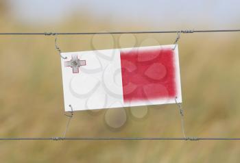 Border fence - Old plastic sign with a flag - Malta