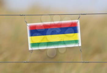 Border fence - Old plastic sign with a flag - Mauritius