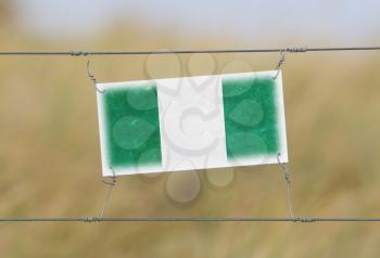 Border fence - Old plastic sign with a flag - Nigeria