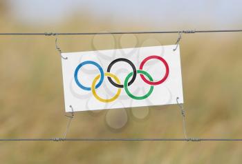 Border fence - Old plastic sign with a flag - Olympic rings