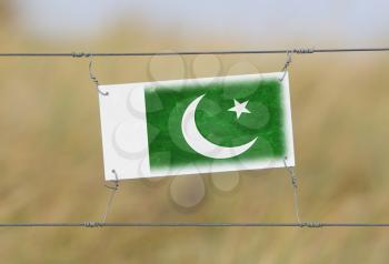 Border fence - Old plastic sign with a flag - Pakistan