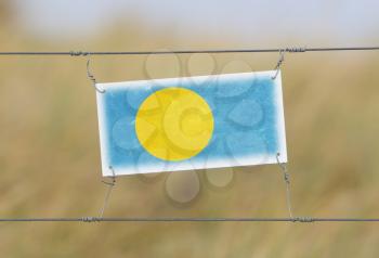 Border fence - Old plastic sign with a flag - Palau