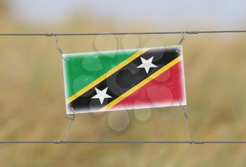 Border fence - Old plastic sign with a flag - Saint Kitts and Nevis