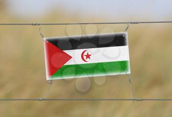Border fence - Old plastic sign with a flag - Western Sahara