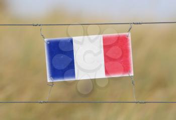Border fence - Old plastic sign with a flag - France