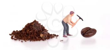 Miniature worker with pickaxe working on a coffee bean
