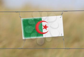Border fence - Old plastic sign with a flag - Algeria