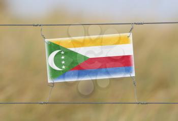 Border fence - Old plastic sign with a flag - Comoros