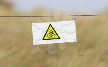 Border fence - Old plastic sign with a flag - Biohazard