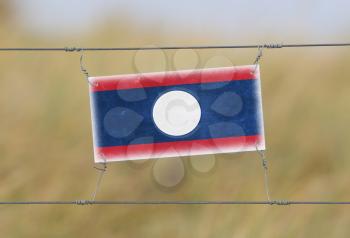 Border fence - Old plastic sign with a flag - Laos