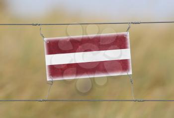 Border fence - Old plastic sign with a flag - Latvia