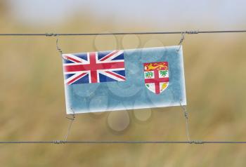Border fence - Old plastic sign with a flag - Fiji