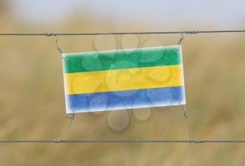 Border fence - Old plastic sign with a flag - Gabon