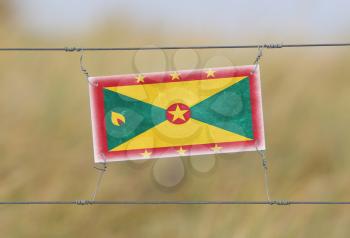 Border fence - Old plastic sign with a flag - Grenada